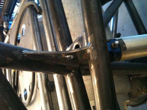 1966 Ford Bronco - Close-up view of a custom roll cage structure, a shock absorber and welded metal brackets.