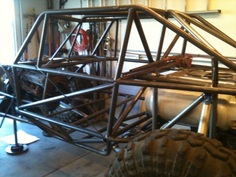 1966 Ford Bronco - This custom-built buggy frame is in a workshop, showing its roll cage, engine, and off-road tires.