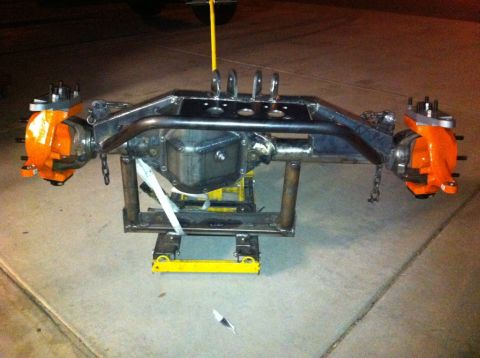 1966 Ford Bronco - Custom differential axle assembly with bright orange brake calipers is supported by a yellow jack.