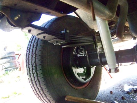 1989 Ford Bronco - Underside view of a vehicle's rear suspension components, including the axle, leaf springs, and a white shock absorber.