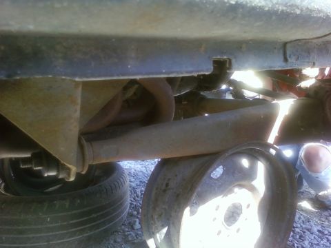 1989 Ford Bronco - The photo shows the rusty undercarriage of a vehicle, with suspension components and exhaust pipes visible.
