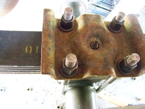 1989 Ford Bronco - A rusty leaf spring bracket with bolts is shown, with yellow markings on the leaf spring.