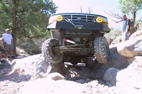 1994 Ford Bronco - A modified Ford Bronco tackles a challenging rocky trail with two people observing.