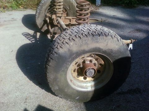 1989 Ford Bronco - Close-up of a vehicle's front axle and suspension system, showing large tires and rusty components.