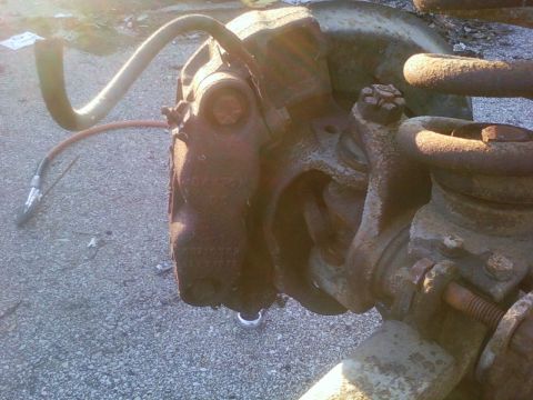 1989 Ford Bronco - Close-up of corroded brake caliper and suspension components, likely from a vehicle undergoing repair or salvage.