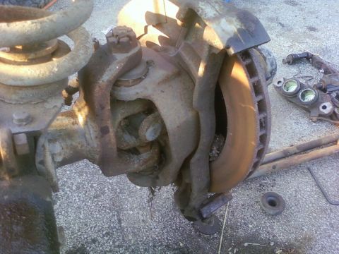 1989 Ford Bronco - Close-up of a heavily rusted vehicle axle assembly, including brake components.