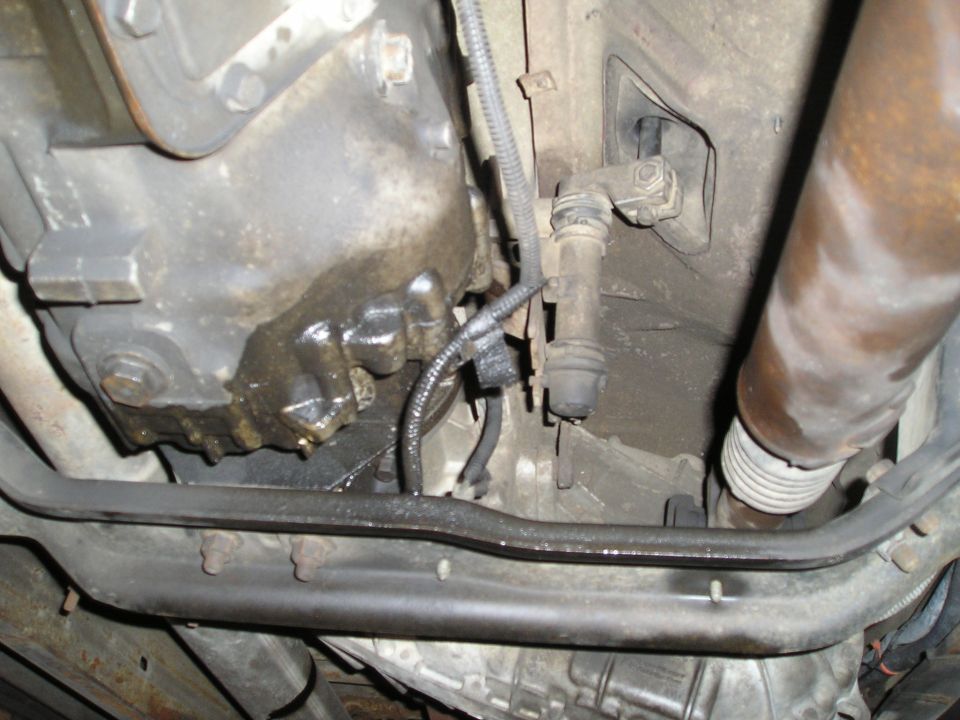 Underside view of a vehicle's transmission and exhaust system, showing some leaks