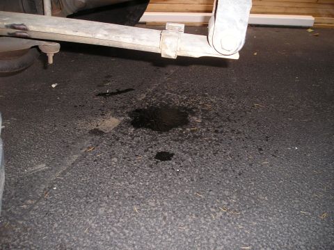 1997 Ford F-250 - A fluid leak is visible on the asphalt beneath the undercarriage of a vehicle.