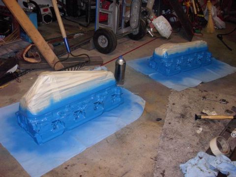 1980 Ford Bronco - Engine blocks are being spray-painted blue in a garage setting, with masking tape protecting some areas.