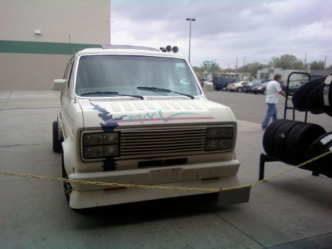 2000 Mercury Grand Marquis - A white van with a custom decal is parked outdoors, with tires on a rack nearby.