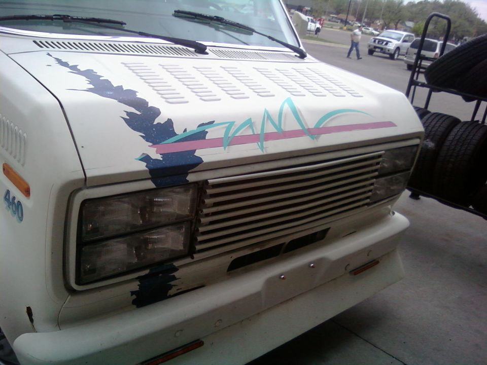Front view of a white van with a blue, pink, and teal graphic on the hood. "460" is visible on the side