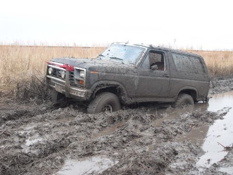 1986 Ford Bronco - This 1986 Ford Bronco is deeply stuck in thick mud, with only its front and side visible.