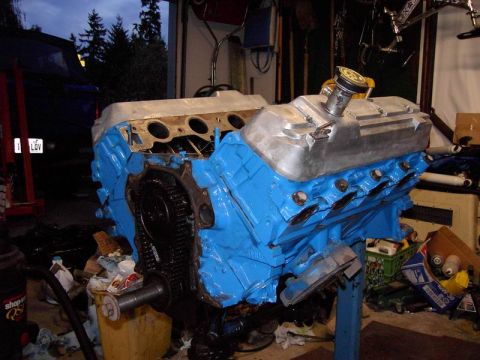 1980 Ford Bronco - Engine assembly in a garage with tools and parts scattered around.