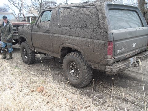 1986 Ford Bronco - Two trucks covered in mud after off-roading.