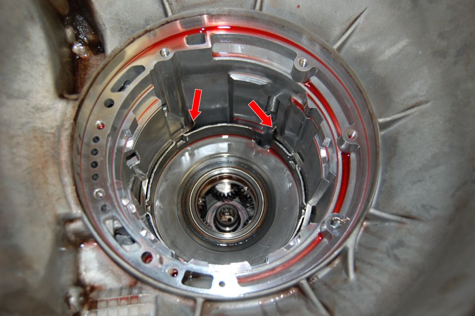 Automatic transmission torque converter housing with red arrows pointing to seals