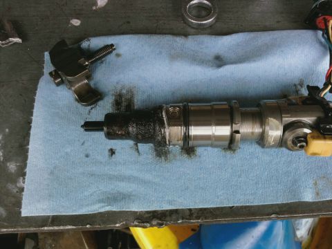 1995 Ford Bronco - A disassembled fuel injector and associated components are laid out on a blue shop towel.