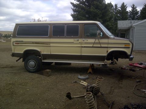 1979 Ford E250 - This van is being worked on, with its front end disassembled and parts lying on the ground.