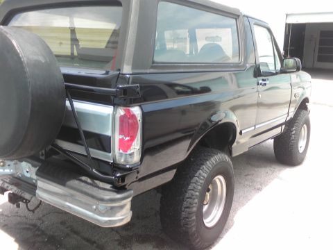 1995 Ford Bronco - This black Ford Bronco is shown from the rear quarter angle, with a spare tire mounted on the back.