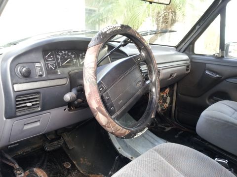 1995 Ford Bronco - The interior of a truck shows the dashboard, steering wheel, and passenger seat.