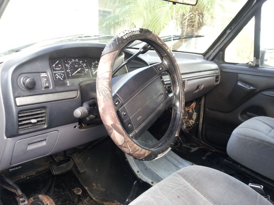 Interior shot of a truck's dashboard and steering wheel with a camouflage cover