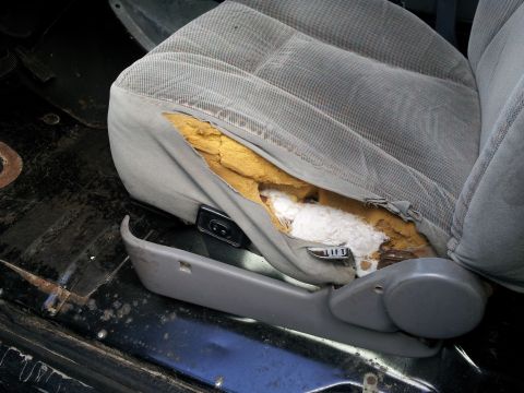 1995 Ford Bronco - The interior of a vehicle shows a damaged seat with visible foam and stuffing.