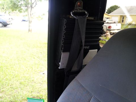 1995 Ford Bronco - The interior of a vehicle is shown, with a seatbelt and an amplifier visible. Outside, other vehicles are parked.