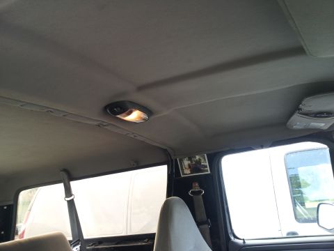 1995 Ford Bronco - The interior of a vehicle is shown, focusing on the headliner, dome light, and a small framed picture on the pillar.