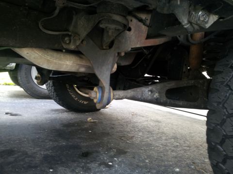 1995 Ford Bronco - A low-angle view shows the complex suspension and exhaust system beneath a vehicle, with tires visible.