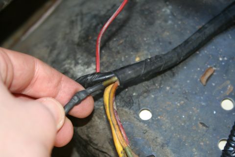 1982 Ford Bronco - Close-up of a hand working on a vehicle's wiring harness, splicing wires.