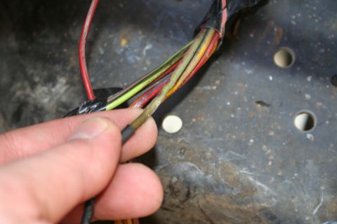 1982 Ford Bronco - A close-up shows a damaged wire within a vehicle's wiring harness, with multiple colored wires bundled together.