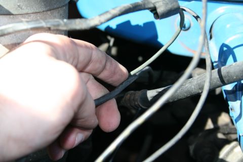 1982 Ford Bronco - Close-up of a hand interacting with engine wiring, with a blue component in the background.