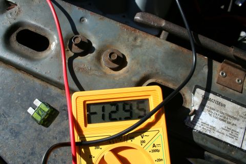 1982 Ford Bronco - A multimeter measures voltage in a vehicle's engine bay, showing -12.95V with a fuse and wiring visible.