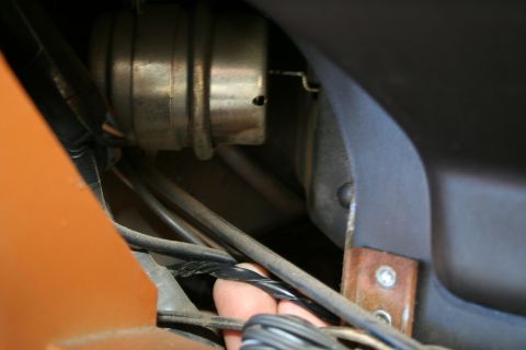 1982 Ford Bronco - Close-up of a hand manipulating wires, with a cylindrical component visible.