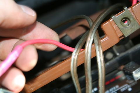 1982 Ford Bronco - A hand manipulates wiring within a vehicle's electrical system, focusing on a connection point.