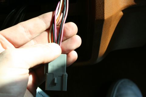 1982 Ford Bronco - A hand holds a wiring harness connector inside a vehicle's interior.