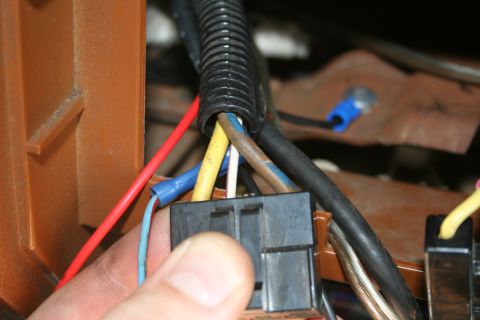 1982 Ford Bronco - A hand connects a wiring harness connector, showing various colored wires and protective tubing.