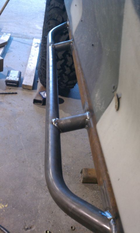 1990 Ford Bronco - Custom metal rock sliders are attached to the side of an off-road vehicle, with a tire visible in the background.