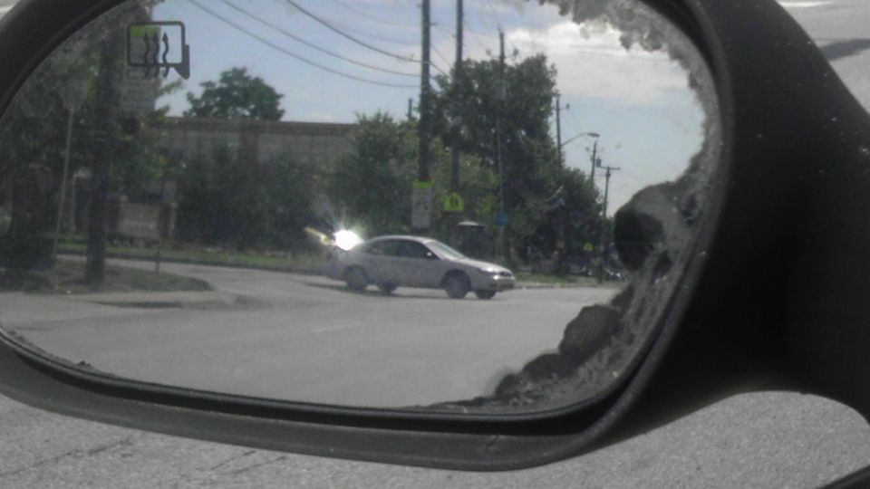 Car seen in side mirror turning at intersection