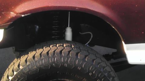 1989 Ford Bronco - This image focuses on the tire and suspension system of a vehicle, with a portion of the maroon-colored body visible.