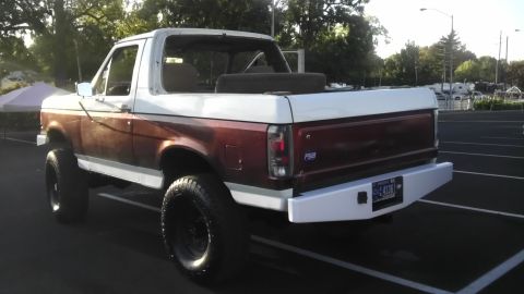 1989 Ford Bronco - This lifted Ford Bronco has a two-tone paint scheme and is parked in a lot.