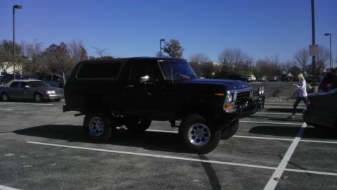 1989 Ford Bronco - A black Ford Bronco is parked in a lot on a sunny day.