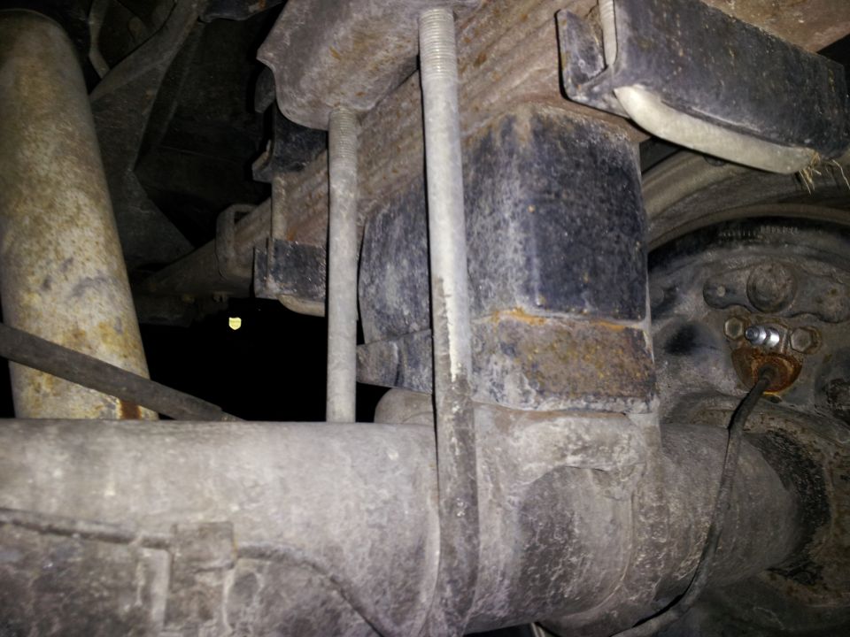 Close-up of rear leaf spring U-bolts and axle housing on a vehicle