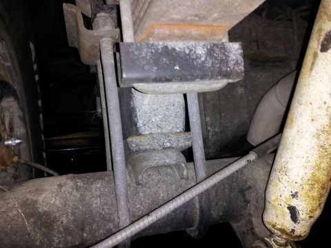 1995 Ford Bronco - Close-up view of the rear axle leaf spring mount and u-bolts, with a shock absorber visible on the right.