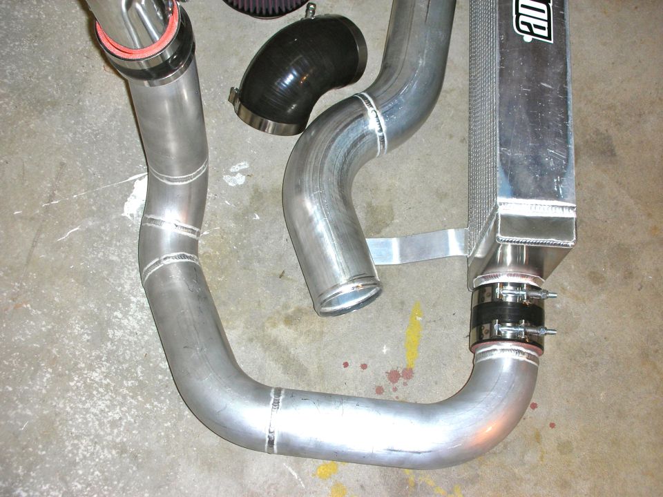 Intercooler piping and air filter for a car's supercharger system. Some parts have ADTR branding