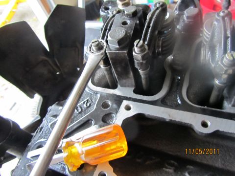 1984 Ford Bronco - Mechanic adjusting engine valves with a wrench and screwdriver.