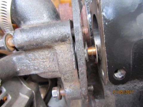 1984 Ford Bronco - This image shows a close-up of an engine component, likely a thermostat housing, with visible bolts and a hose clamp.