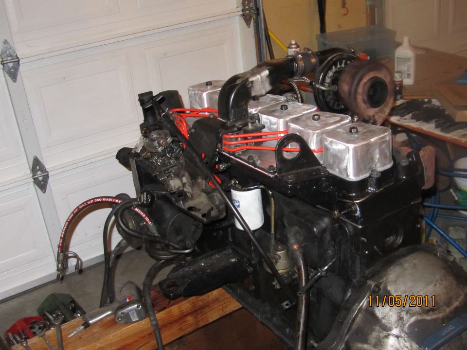 engine block with turbo, fuel injectors, and oil filter, sitting on wooden supports
