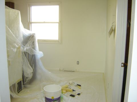 1984 Ford Mustang - A room is prepared for painting, with furniture covered and supplies laid out on the floor.