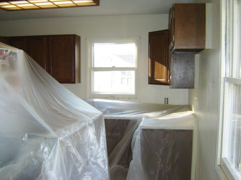 1984 Ford Mustang - A kitchen scene with counters and cabinets covered in protective plastic sheeting, likely during renovation or painting.