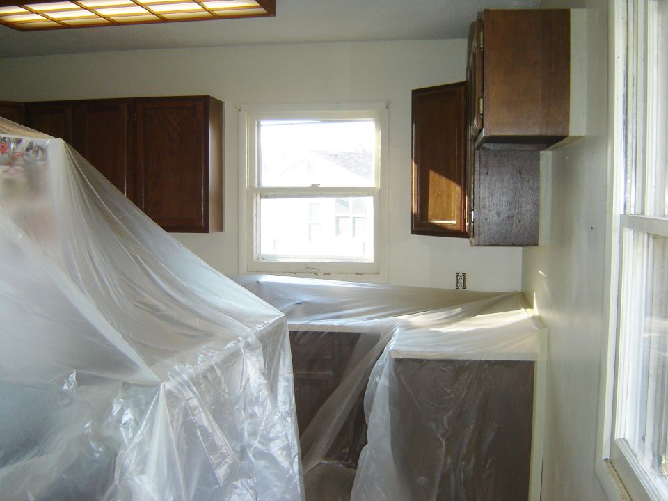 Kitchen counters and cabinets covered in plastic sheeting